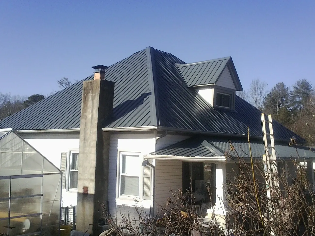 Dark blue standing seam metal roof on a white farmhouse with dormer — Slate & Tile Roof Repair by Roofing Brothers in Whittaker