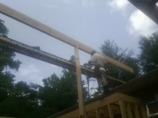 Carpenter setting a ridge beam over a new addition frame — Ice Dam Removal by Roofing Brothers in Whittaker