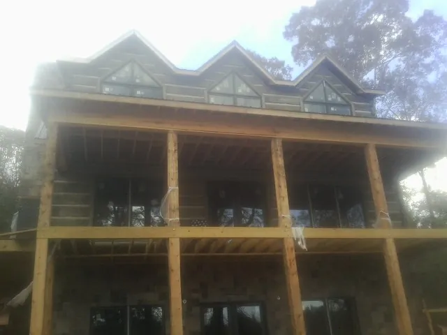Dormers and porch framing on a large log home under construction — Roof Coating work by our crew in Whittaker
