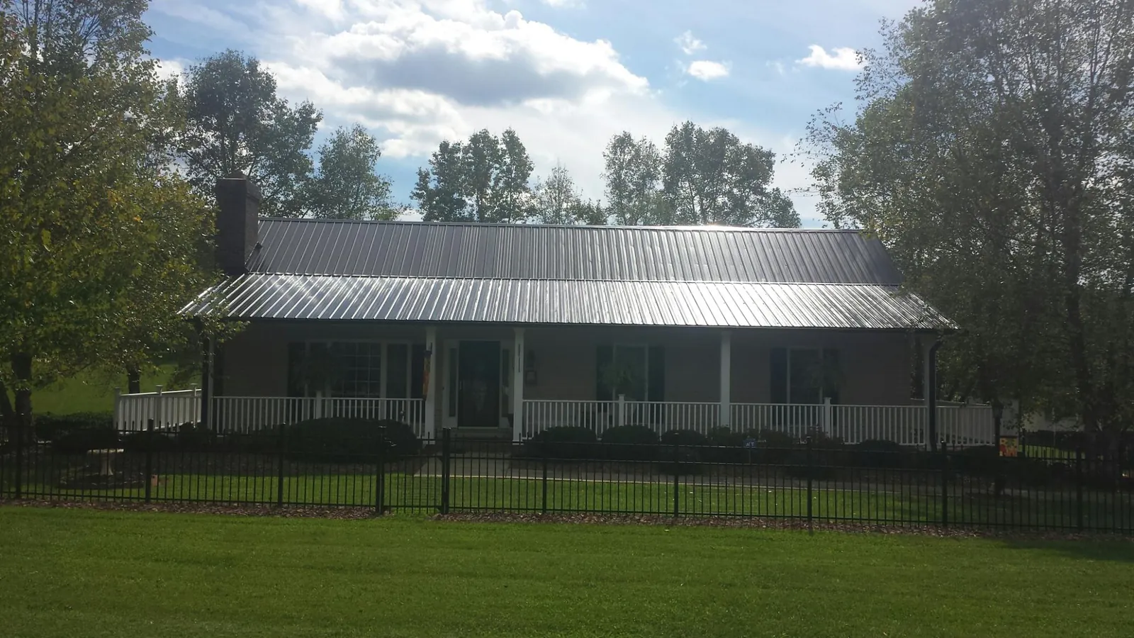 Gray metal roof on a brick ranch with a full width front porch — Gutter Guard Installation work by our crew in Whittaker