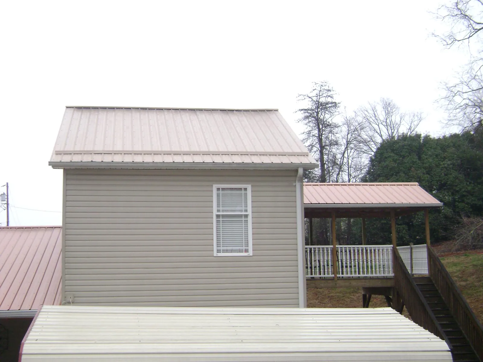 Tan metal roofs on a two story addition and attached porch, from a Roof Replacement job in Whittaker